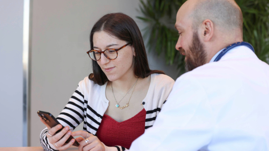 A doctor points something out to a patient on their iPhone